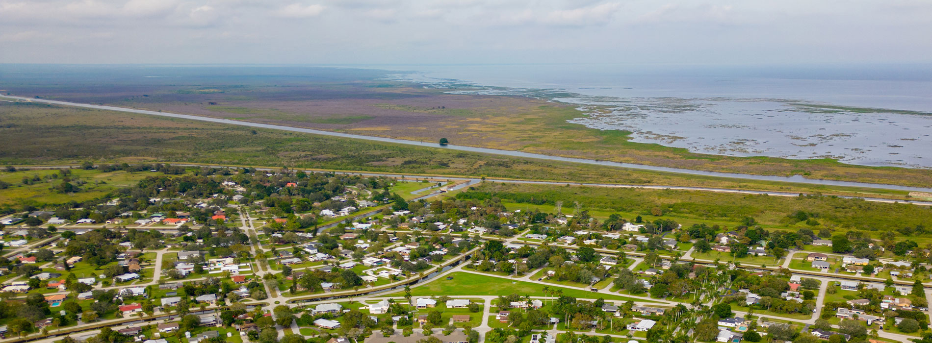 The image shows an aerial view of a residential area with houses, roads, and water bodies, taken from a high angle perspective.