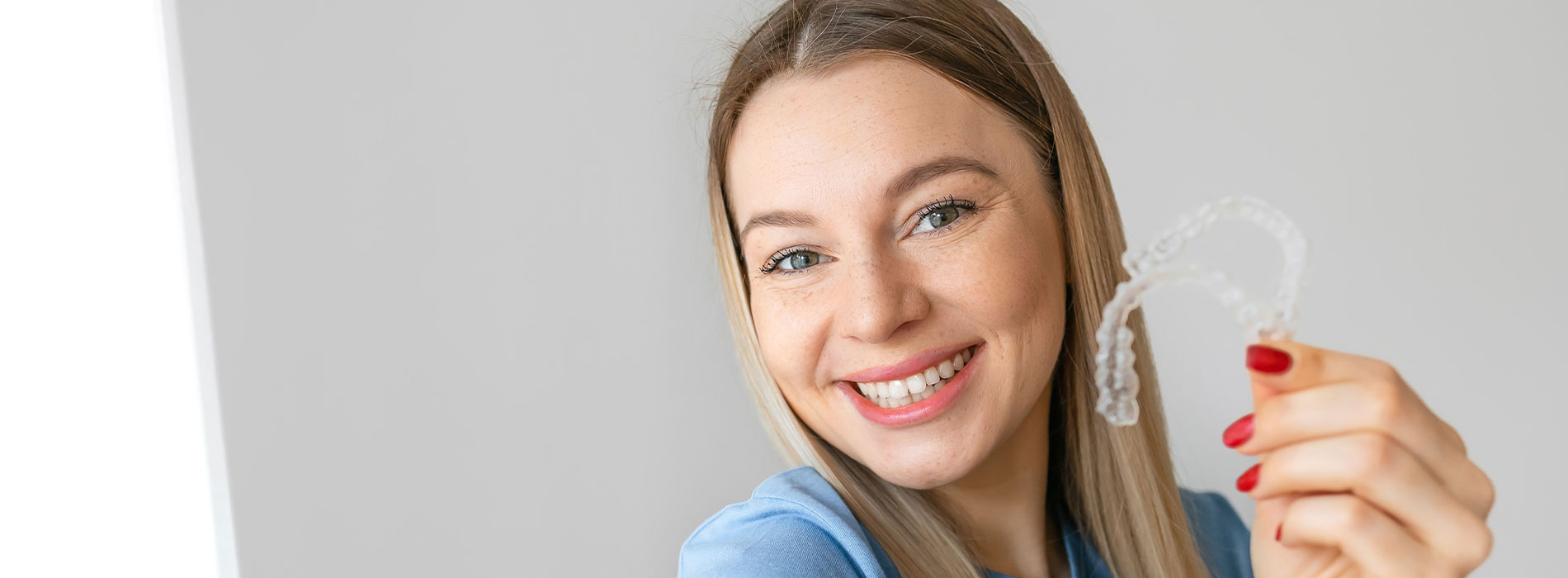A woman holding a key with a smile, set against a white background.