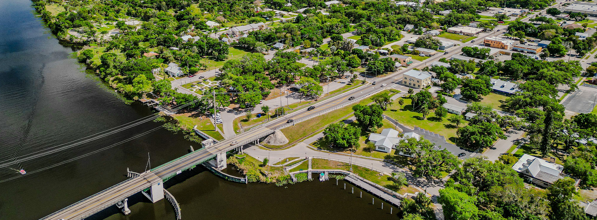 The image depicts a bird s eye view of a suburban area with various buildings, roads, and green spaces, captured during daylight.