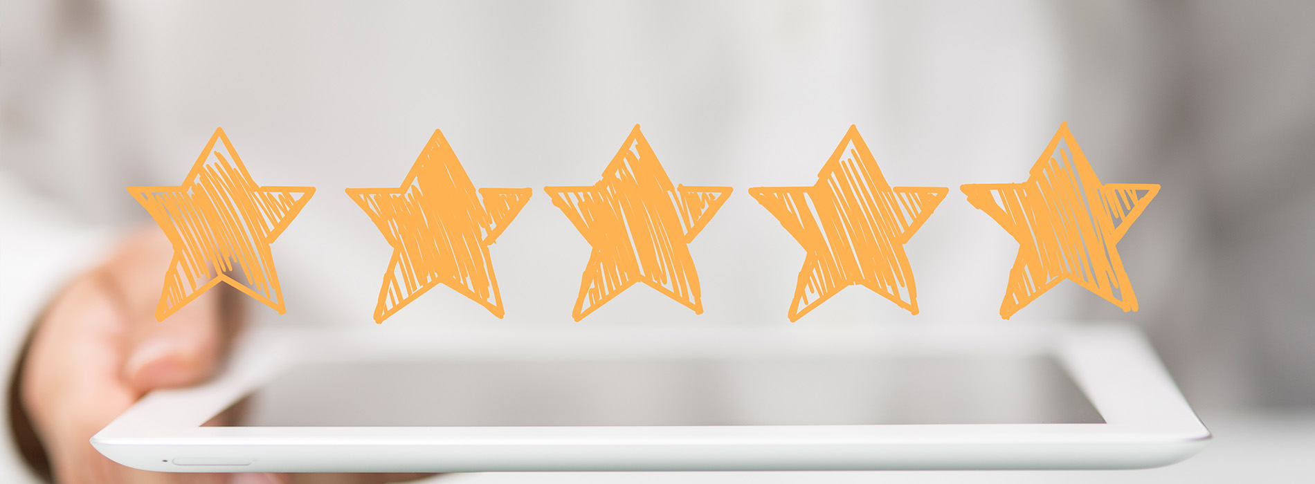 The image displays a hand holding a tablet with an app showing star ratings, set against a blurred background featuring a person s arm and hand.